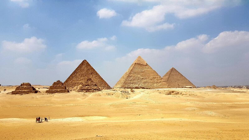The Great Pyramids of Giza standing tall in the desert under a blue sky