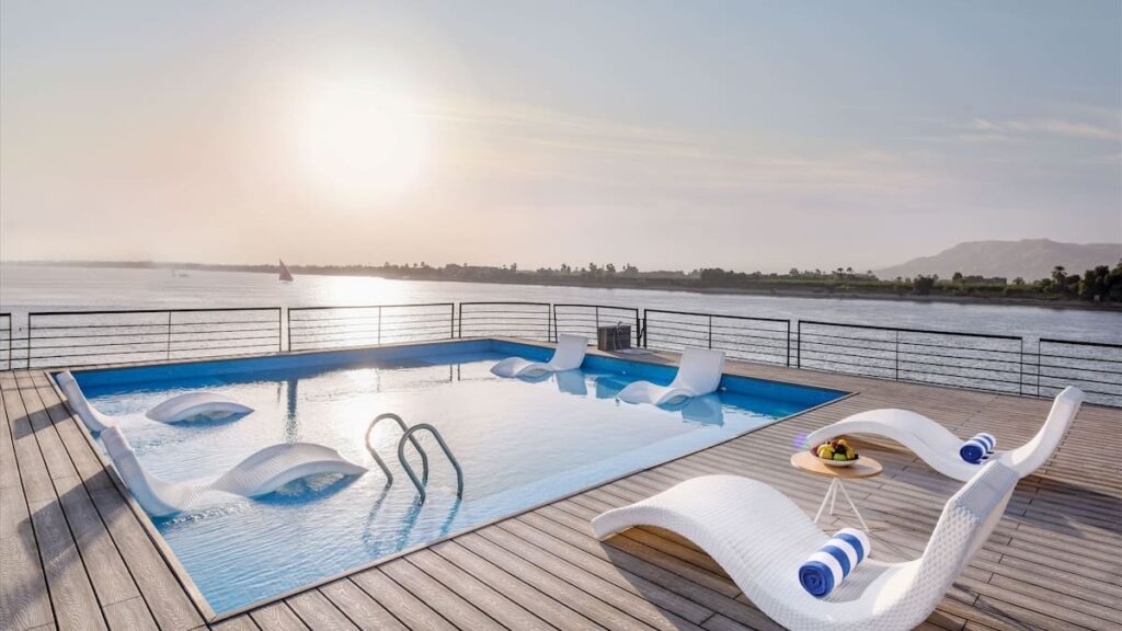 Infinity pool on a sundeck overlooking a river at sunset.
